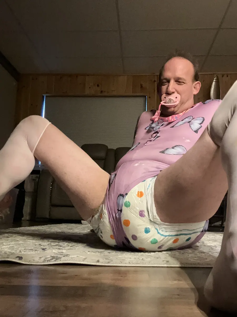 A person reclines on a rug in a purple butterfly top and white polka-dot bottoms, viewed from the floor.