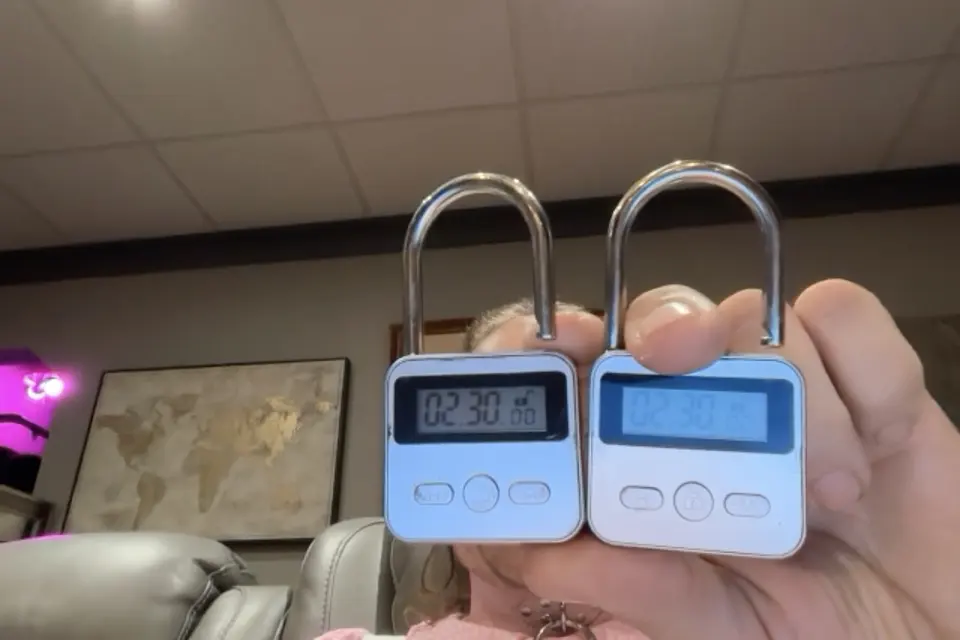Two blue-and-white digital padlocks are held up in front of a living room background.