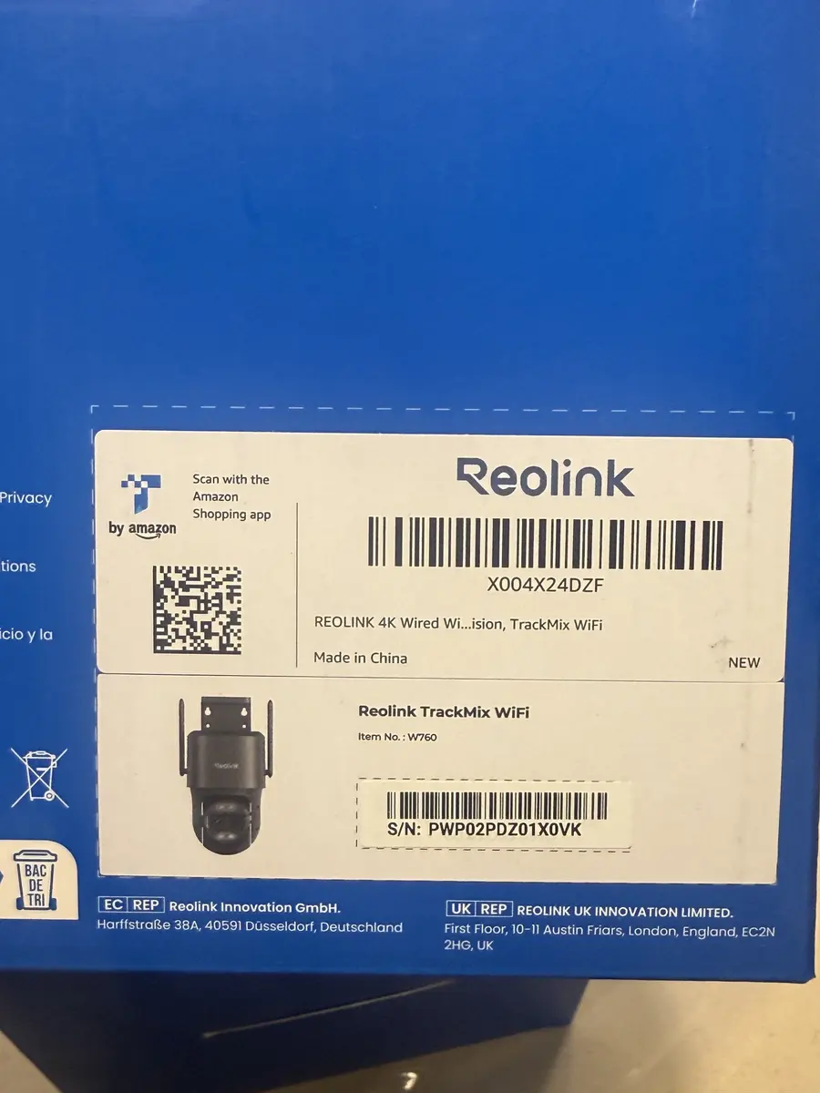 Blue Reolink camera package with white labels, barcodes, a QR code, and a small camera illustration on a tabletop.